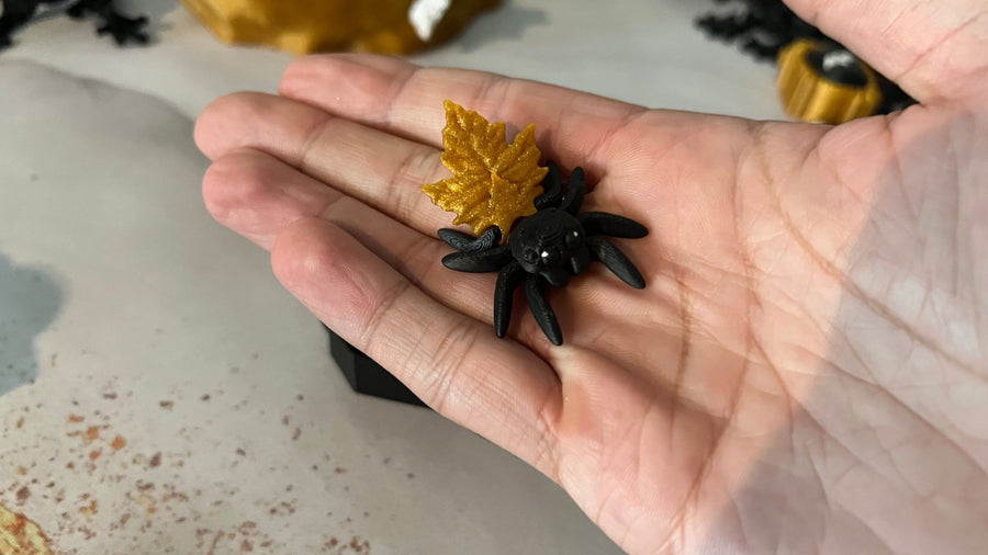 Jeremy the Jumping Spider 3D printed fidget toy in Midnight Black, holding a leaf